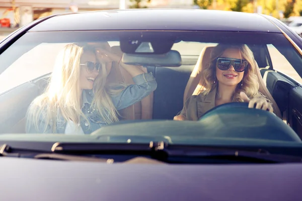 Foto a través del parabrisas de rubias con gafas de sol mientras conducen en coche —  Fotos de Stock