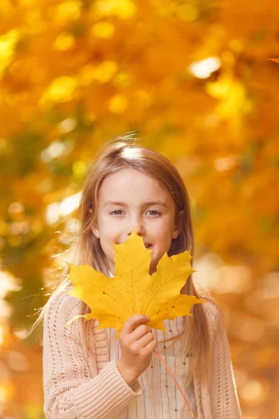 Photo of girl with leaf of maple in autumn park in afternoon — Stock Photo, Image