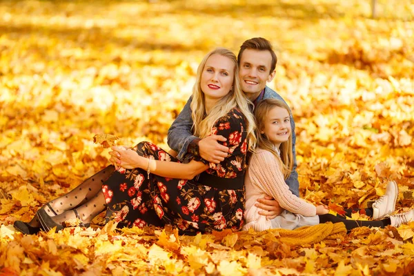 Foto de mãe, pai e filha sentados em folhas no outono — Fotografia de Stock