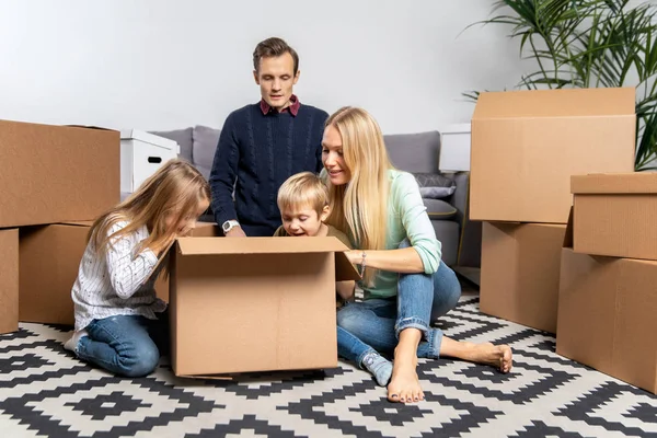 A szülők és a gyermekek között, karton dobozok, új lakás fénykép — Stock Fotó