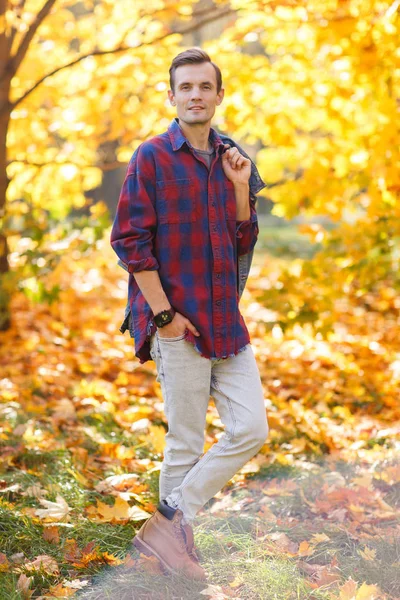 A fiatal barna kockás ing-őszi parkban teljes hosszúságú fénykép — Stock Fotó