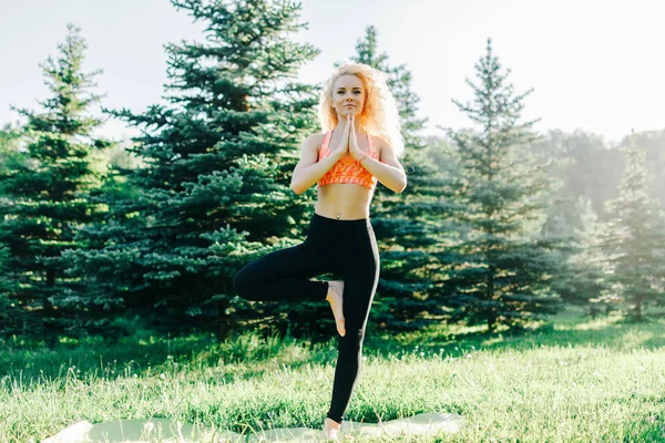 Foto van jonge curly-haired sport vrouw beoefenen van yoga op tapijt — Stockfoto