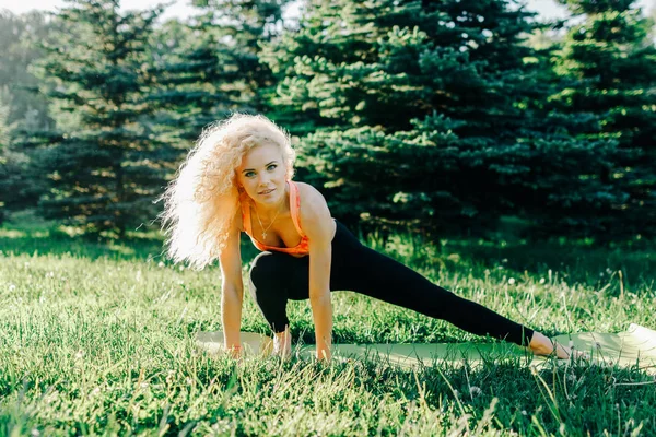Beeld van jonge curly-haired sport vrouw beoefenen van yoga op tapijt — Stockfoto