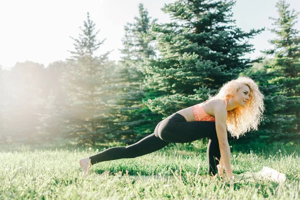 Beeld van jonge curly-haired sport vrouw beoefenen van yoga op tapijt — Stockfoto