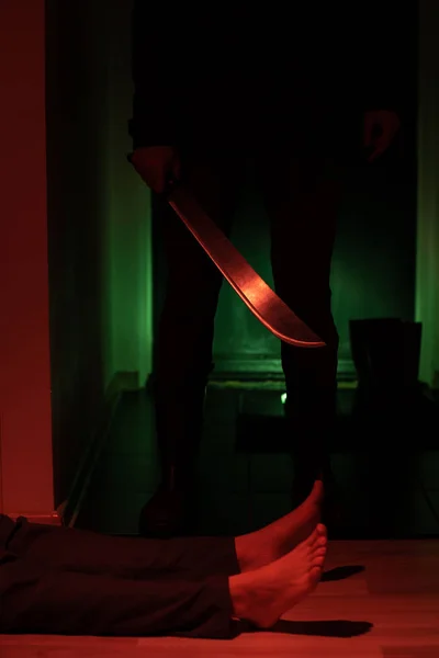Imagen de ladrón con machete y hombre acostado en el suelo en apartamento oscuro — Foto de Stock