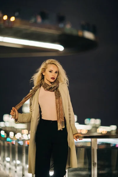 Fotoseite der Blondine im Mantel auf Brücke auf verschwommenem Hintergrund — Stockfoto