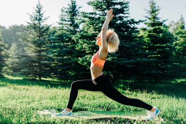 Фото молодой кудрявой спортивной женщины, практикующей йогу на ковре — стоковое фото