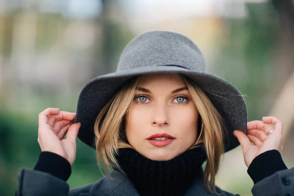 Retrato de mujer joven en sombrero gris sobre fondo borroso de plantas de la ciudad — Foto de Stock