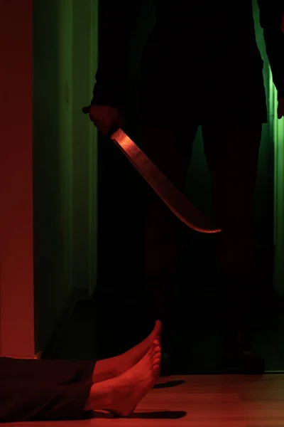 Foto de ladrón con machete en habitación oscura y hombre acostado en el suelo — Foto de Stock