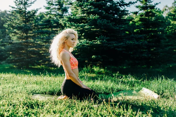 Immagine di giovane donna sportiva dai capelli ricci che pratica yoga sul tappeto — Foto Stock