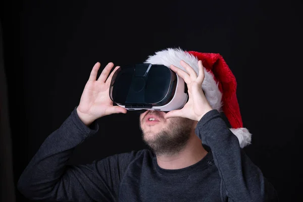 Bilden av unga brunet i Santas cap och glasögon av virtuell verklighet — Stockfoto