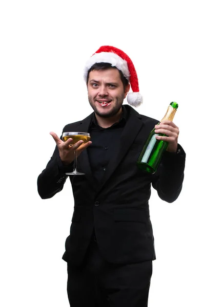 Imagen del hombre en gorra de Santas, con caña de caramelo en la boca, con copa de champán, botella en las manos  . — Foto de Stock