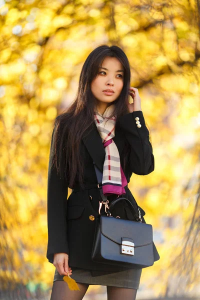 Foto de chica oriental con harina, en pelaje negro en el bosque de otoño —  Fotos de Stock