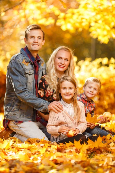 Kép a vidám szülők és a gyermekek, ül az őszi park — Stock Fotó