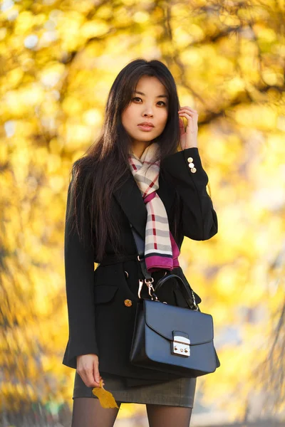 Image de fille orientale avec de la farine, en manteau noir dans la forêt d'automne — Photo