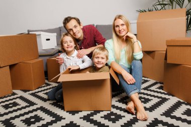 Karton kutular arasında katta oturan çocuklu genç çift