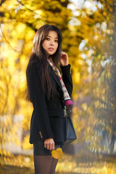 Foto de mujer oriental con harina, en pelaje negro en el bosque de otoño —  Fotos de Stock