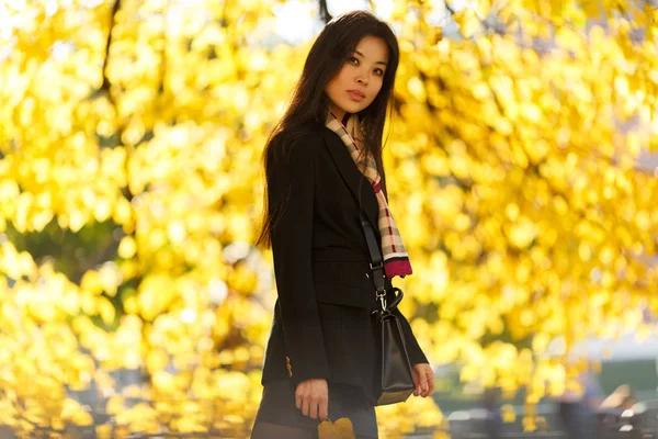 Foto de menina oriental com farinha, em casaco preto na floresta de outono — Fotografia de Stock