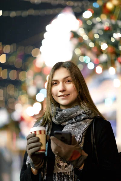 Bild einer glücklichen Frau mit Glas und Handy in der Hand am Abend zum Spaziergang — Stockfoto