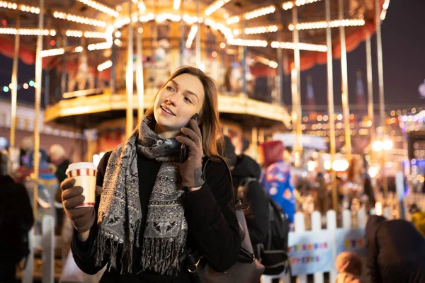 Bild einer glücklichen Frau mit Glas und Handy in der Hand am Abend beim Spaziergang — Stockfoto