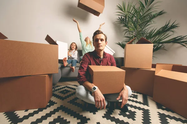 Фото мужчины, сидящего на полу среди картонных коробок и смешной женщины с сыном и дочерью — стоковое фото