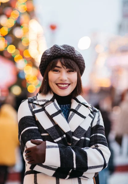 Photo of happy brunette , blurred background with burning garland