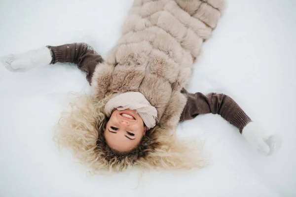 Φωτογραφία: ξανθιά ξαπλωμένη στο χιόνι με τα πόδια — Φωτογραφία Αρχείου