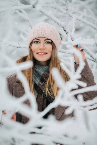 Портрет улыбающейся женщины в шляпе на прогулке в зимнем лесу — стоковое фото