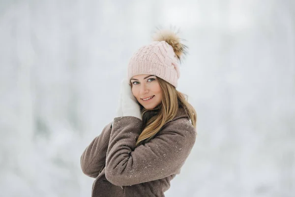 Porträtt av glada blond flicka i hatt på promenad i vinter skog — Stockfoto