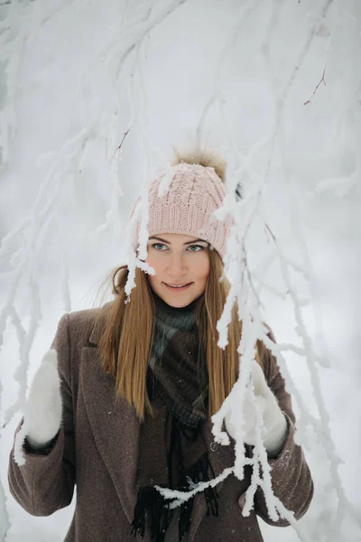 Foto de la mujer rubia feliz en sombrero a pie en el bosque de invierno —  Fotos de Stock