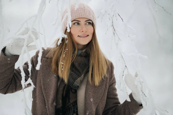 Foto de la mujer rubia feliz en sombrero a pie en el bosque de invierno —  Fotos de Stock
