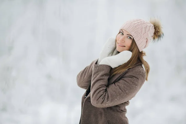 Ritratto di ragazza bionda felice in cappello a piedi nella foresta invernale — Foto Stock