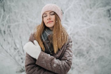 Kış ormandaki yürüyüşte şapkalı gülümseyen kadın portresi
