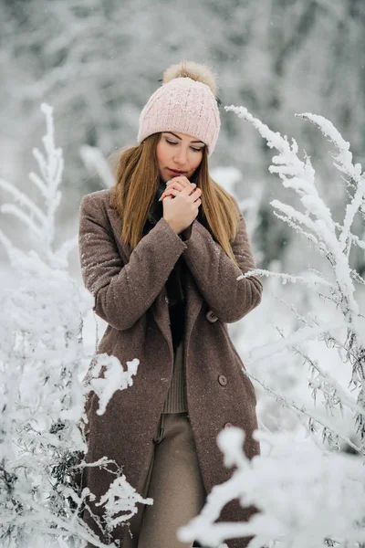 Porträtt av blond kvinna i hatt tittar på kameran på promenad i vinter skog — Stockfoto