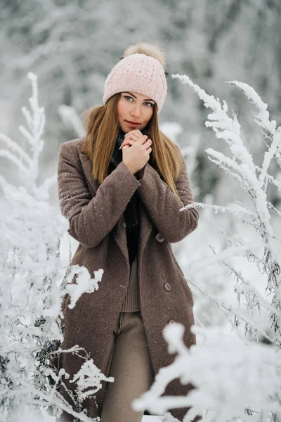 Retrato de mujer rubia en sombrero mirando a la cámara en el paseo en el bosque de invierno —  Fotos de Stock