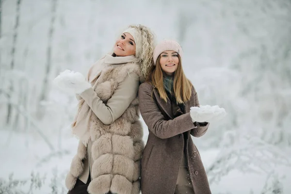 Porträtt av två glada blonda kvinnor i hatt på promenad i vinter skog — Stockfoto