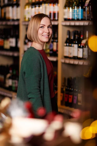 Immagine di donna felice su sfondo sfocato di scaffali con bottiglie di vino — Foto Stock