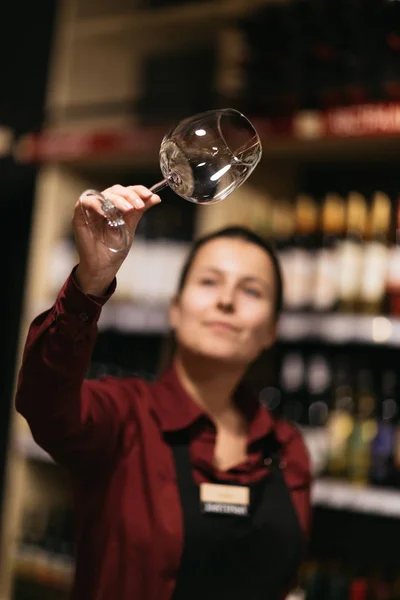 Immagine di donna con bicchiere di vino su sfondo sfocato di scaffali con bottiglie — Foto Stock
