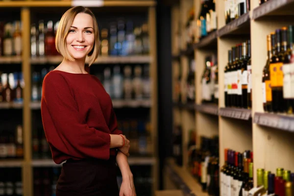 Photo de femme blonde heureuse en magasin avec du vin — Photo