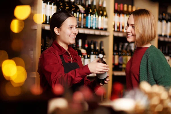 Immagine di due donne felici su sfondo sfocato di scaffali con bottiglie di vino — Foto Stock