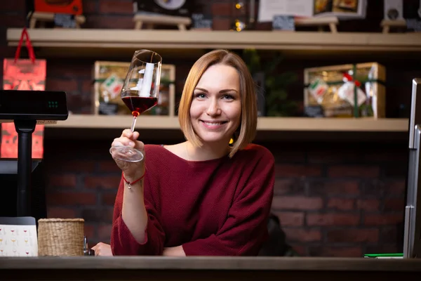 Foto di donna felice venditore con bicchiere di vino in piedi dietro registratore di cassa — Foto Stock