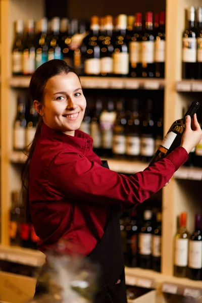 Foto einer jungen Frau mit Flasche in der Hand in einem Weinladen — Stockfoto