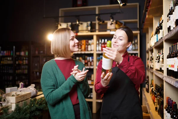 Imagem de mulheres jovens com garrafa de vinho nas mãos na loja — Fotografia de Stock