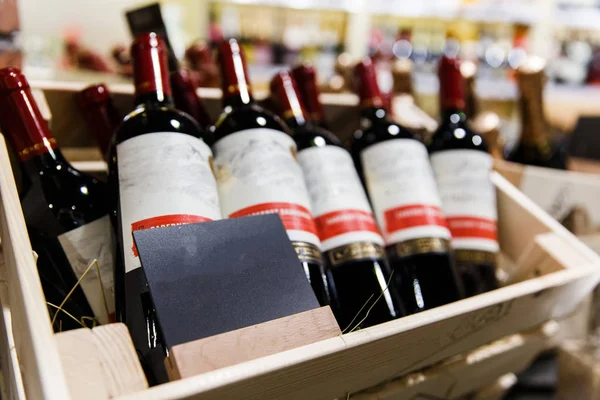 Several bottles of wine with empty labels in wooden boxes.