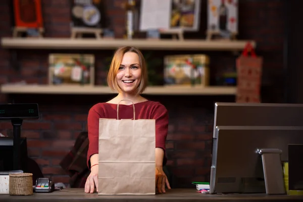 Foto einer glücklichen blonden Verkäuferin mit Papiertüte — Stockfoto