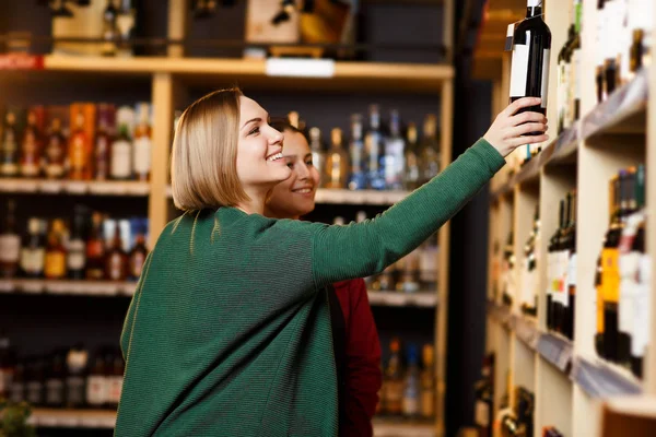 Immagine di donna su sfondo sfocato di scaffali con bottiglie di vino — Foto Stock