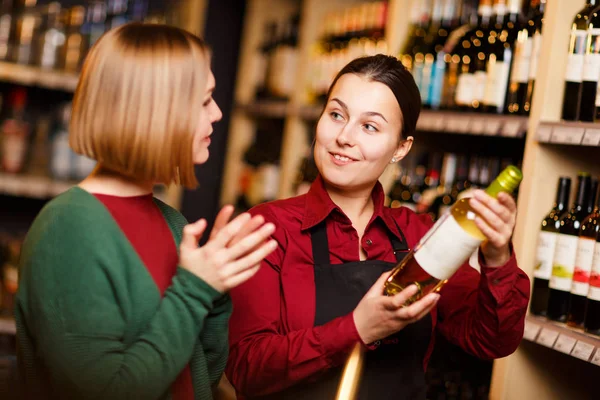 Photo de deux jeunes femmes avec bouteille dans les mains au magasin d'alcool — Photo