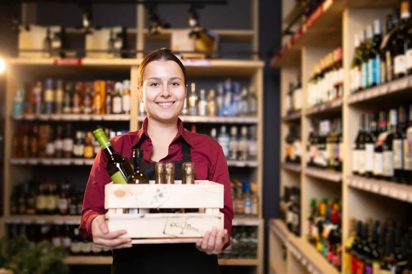 Foto di giovane bruna venditore con scatola di legno con vino in negozio — Foto Stock