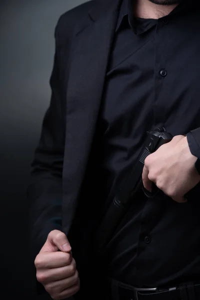 Hombre de traje negro con pistola en las manos. — Foto de Stock