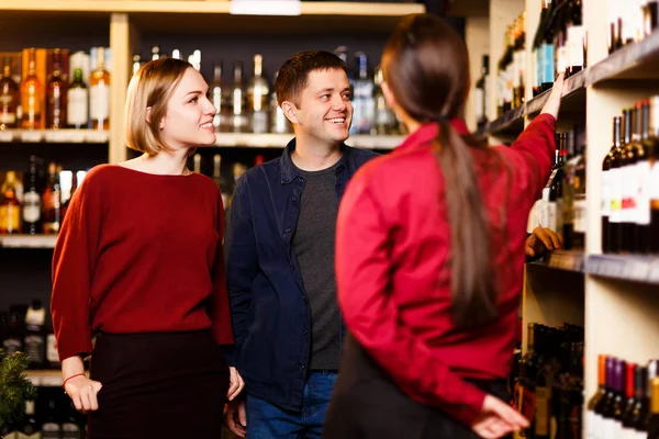 Foto di donna, uomo e venditore da dietro in negozio con il vino — Foto Stock